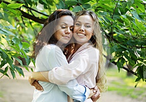 mature mother and adult daughter hugging in the park on a summer day