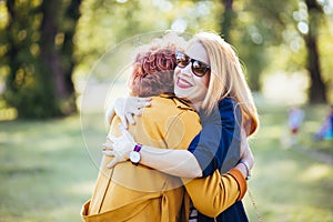 Mature mother and adult daughter hugging in the park