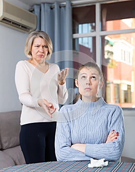 Mature mother and adult daughter quarrelling in domestic interior