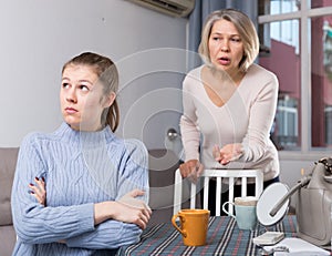 Mature mother and adult daughter quarrelling in domestic interior