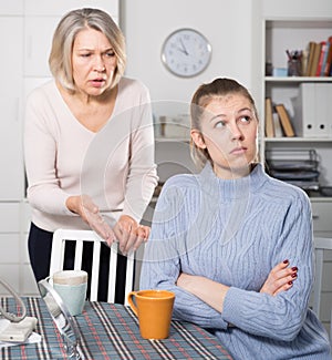 Mature mother and adult daughter quarrelling in domestic interior