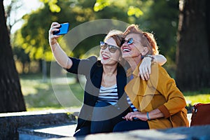 Mature mother and adult daughter taking selfie