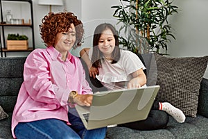 Mature mother and down syndrome daughter at home using computer laptop