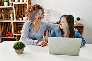 Mature mother and down syndrome daughter using computer laptop at home