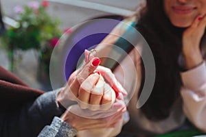 Mature mother and her young daughter sit together in cafe or restaurant. Cut view of girl holding engagement ring with