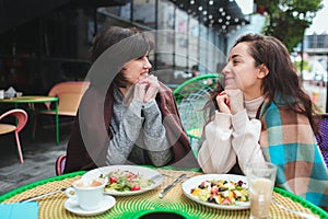 Mature mother and her young daughter sit together in cafe or restaurant. Lovely women spend time with each other. Mother