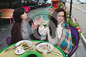 Mature mother and her young daughter sit together in cafe or restaurant. Misunderstanding in family. Girl and mature