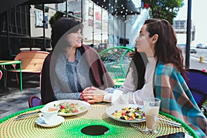 Mature mother and her young daughter sit together in cafe or restaurant. Women with good relationships as family talking