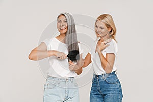 Mature multiracial women wearing t-shirts brushing hair together photo
