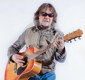Mature musician plays acoustic guitar studio portrait.