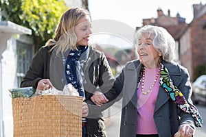 Mature Neighbor Helping Senior Woman To Carry Shopping