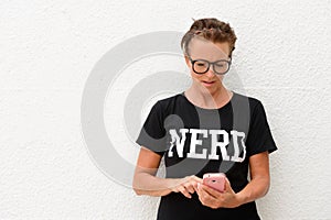 Mature nerd woman wearing big eyeglasses and standing against white background outdoors while using mobile phone and