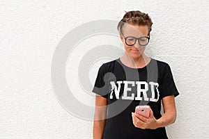 Mature nerd woman wearing big eyeglasses and standing against white background outdoors while using mobile phone