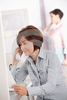 Mature office worker woman using landline phone