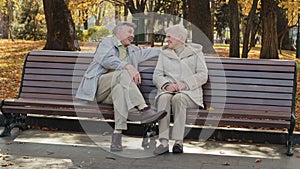 Mature old caucasian couple grandparents sit on bench senior pensioner man cuddling closer to middle aged single woman