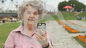 Mature old woman takes photos using a smart phone