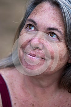 Mature older woman with gray hair smiling against natural background