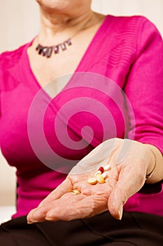 Mature older woman holding tablets or pills