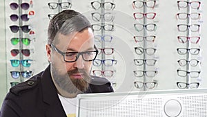 Mature optometrist working on a computer at his store