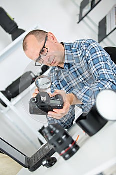 Mature photographer checking camera with magnifying glas