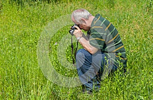 Mature photographer taking a photo of Common Blue butterfly