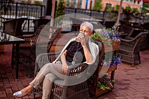 Mature pleasant woman drinking tea in her favourite coffee shop