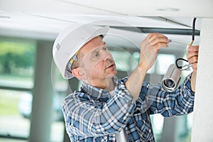 Mature professional handyman replacing light bulb