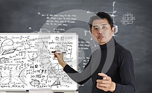 Mature professor teaching mathematics to students in classroom. Teacher man solving math problem while writing on white board with