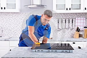 Mature Repairman Examining Induction Stove