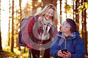 Mature Retired Couple Walk In Fall Or Winter Countryside Using Map Or Navigation App On Mobile Phone