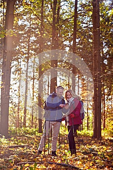 Mature Retired Couple Walk In Fall Or Winter Countryside Using Map Or Navigation App On Mobile Phone