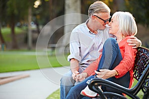 Mature Romantic Couple Sitting On Park Bench Together