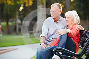 Mature Romantic Couple Sitting On Park Bench Together