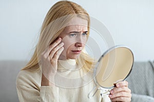 Mature Sad Woman Looking At Wrinkles In Mirror