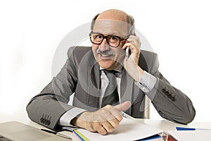 Mature senior business man talking on mobile phone at office desk working happy and gesturing funny