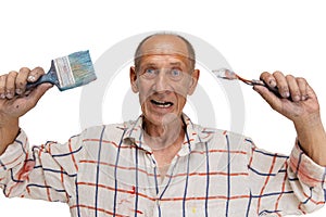 Mature or senior grey painter with a brush standing in front of camera. Funny man in a paint-stained shirt fooling