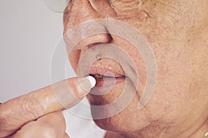 Mature senior middle aged woman holding pill taking painkiller