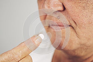 Mature senior middle aged woman holding pill taking painkiller