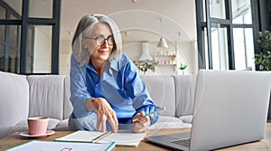 Mature senior woman having video call virtual class at home.