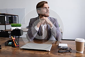 mature serious businessman sitting at the table thoughtfully looking out the window
