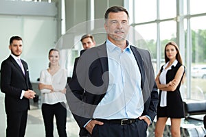 Mature smiling business manager crossing his arms in front of his business team.