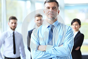 Mature smiling business manager crossing his arms in front of his business team.