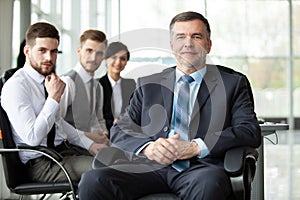 Mature smiling business manager in front of his business team