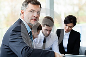 Mature smiling business manager in front of his business team