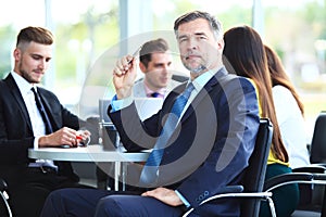 Mature smiling business manager in front of his business team.