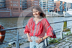 Mature smiling woman in embroidered shirt looking at camera, outdoor