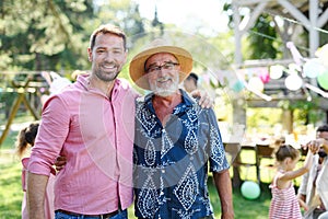 Mature son with his elderly father at a summer garden party outdoors. Concept of Father& x27;s Day and paternal love at