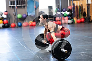 Mature sportive woman lifting weights in the gym