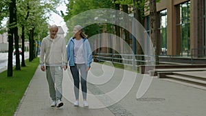 Mature sporty couple holding hands while walking together in the street. Love and communication concept.