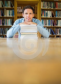 Mature student with stack of books at desk in the library